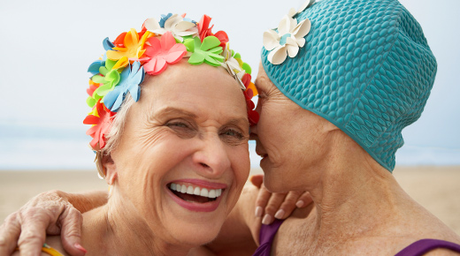 Two senior women in swim caps at the beach