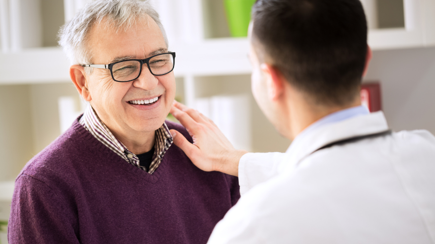 A senior citizen male receives care from a doctor.