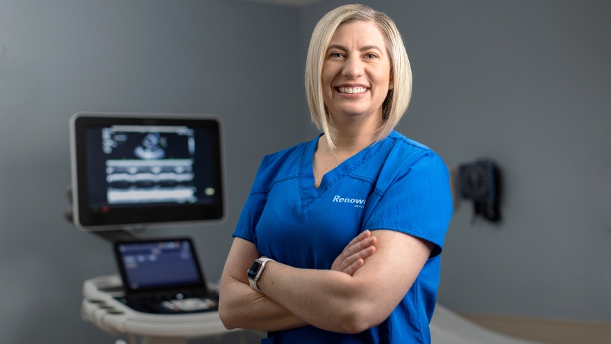An echo technologist poses in front of an echo ultrasound machine.