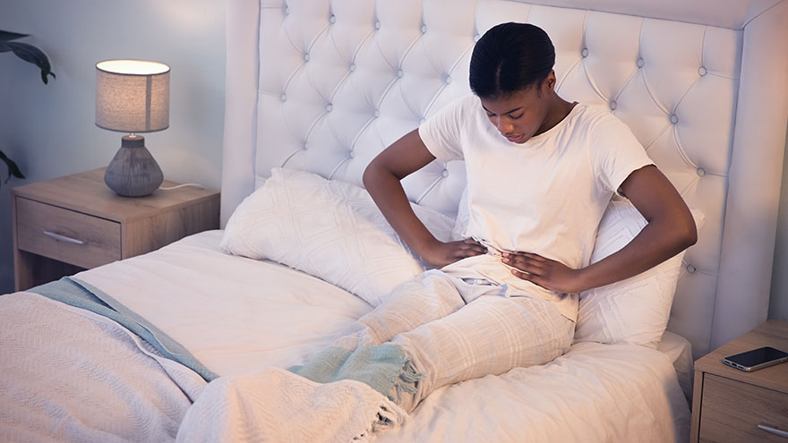 Woman on bed experiencing pelvic pain