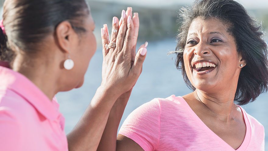 Two African American women in pink, high fives
