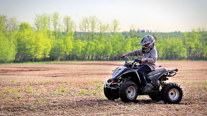A young boy quading in a spring field.