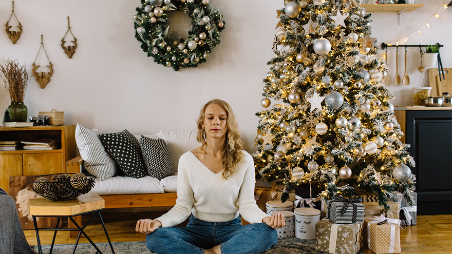 woman sitting in front of christmas tree meditating 