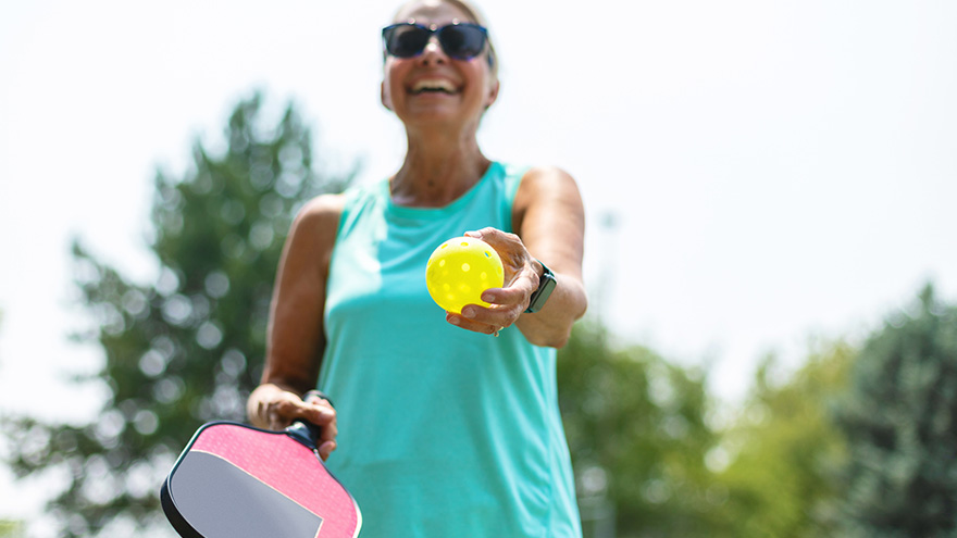 Woman holding pickleball and paddle