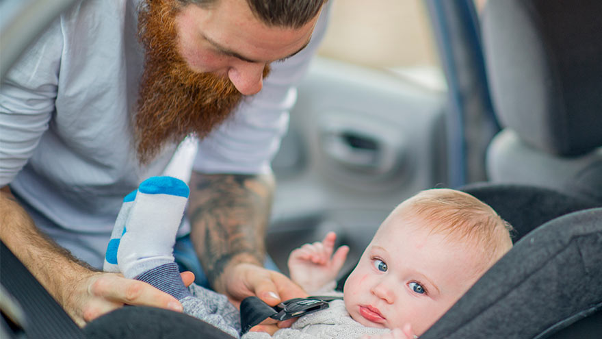Father assuring child is properly restrained in car seat