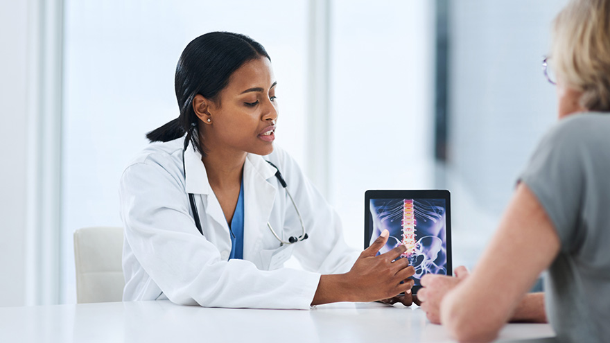 doctor sitting with senior woman patient showing her spine scan image