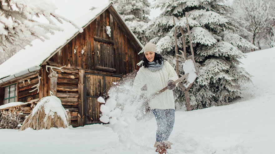 Woman snowshoveling at her cabin