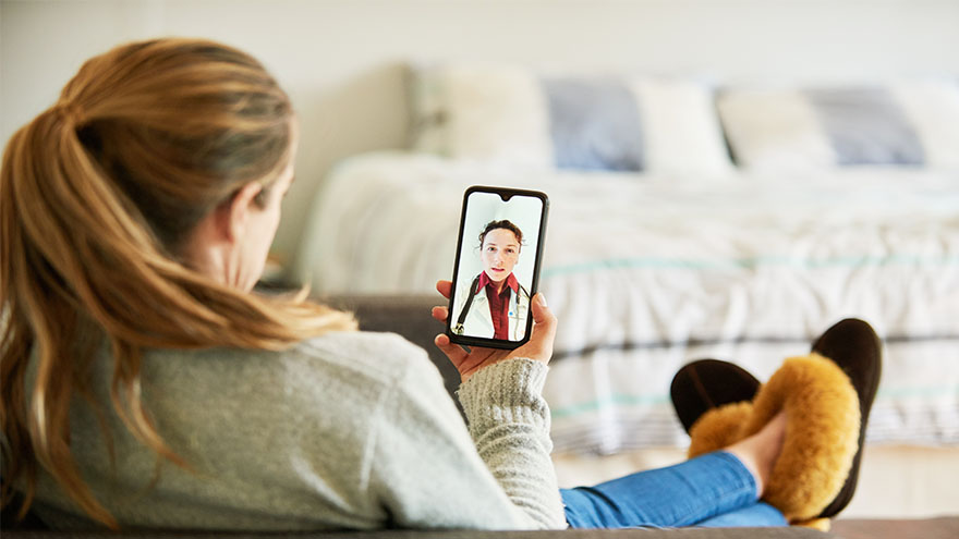 Women sitting on her couch on a video call with a healthcare provider