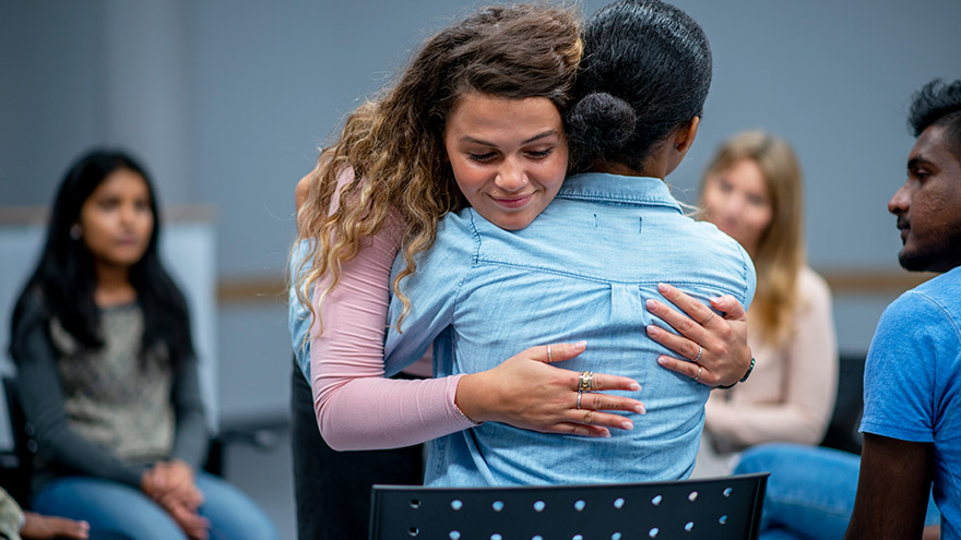 Teens embracing during group therapy session