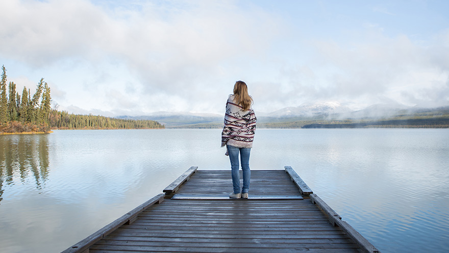 Woman standing at the end of a pier overlooking a lake