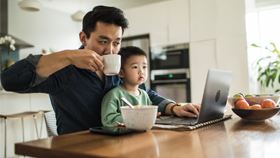Father with a son on his computer in the kitchen